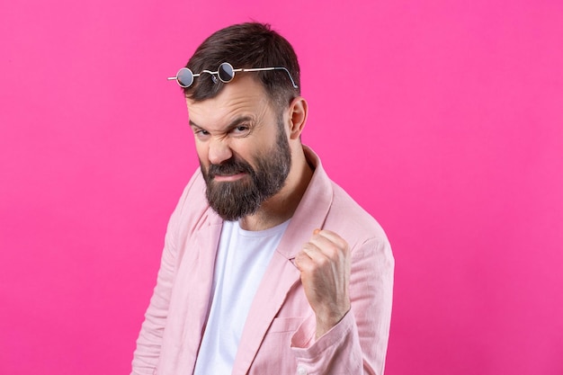 Bebaarde man gekleed in een roze jasje met een bril emotioneel studioportret