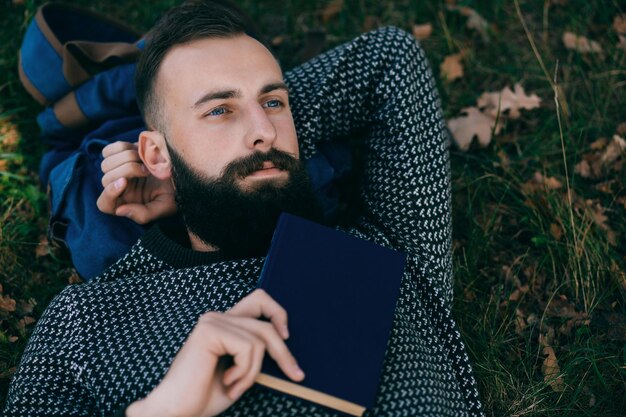 Bebaarde man hipster een boek lezen en ontspannen in parkx9xA