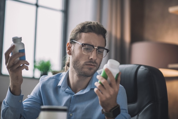 Bebaarde man in blauw shirt lezen over vitamines