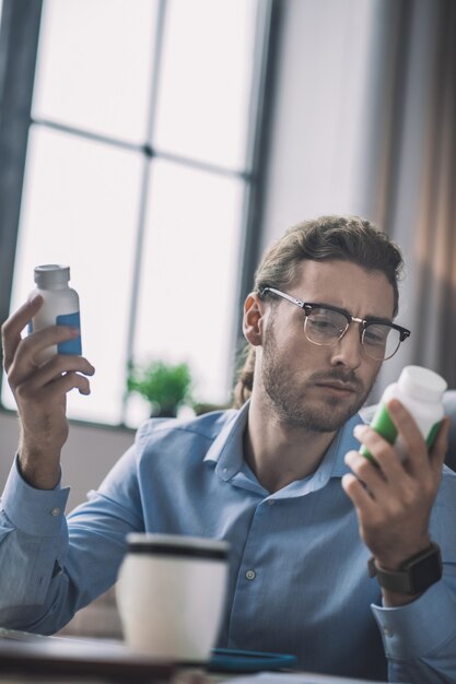 Bebaarde man in blauw shirt lezen over vitamines