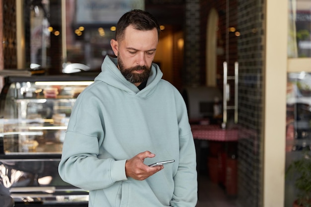 Bebaarde man in casual kleding met behulp van zijn smartphone