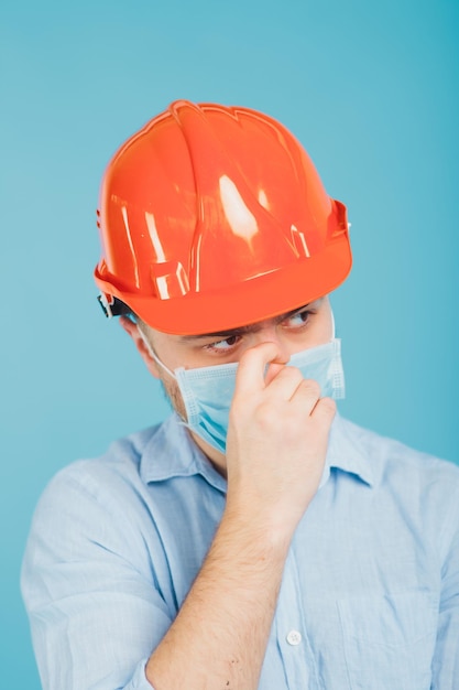 bebaarde man in een beschermende oranje helm en masker op een blauwe achtergrond