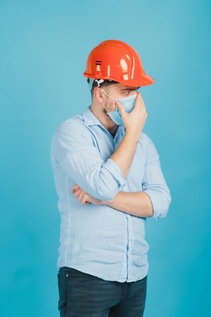 bebaarde man in een beschermende oranje helm en masker op een blauwe achtergrond