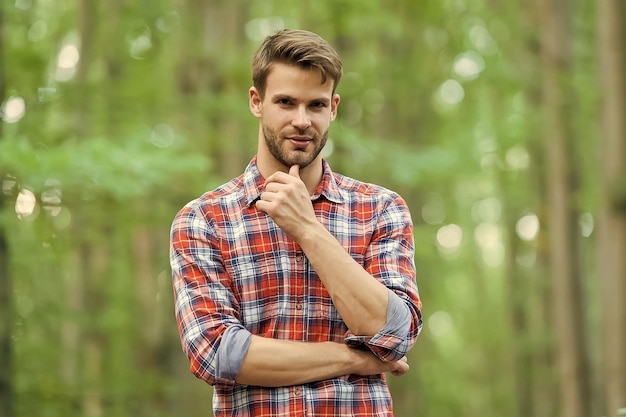 Bebaarde man in geruit hemd met ongeschoren gezichtshaar reizen in de zomer natuur baard