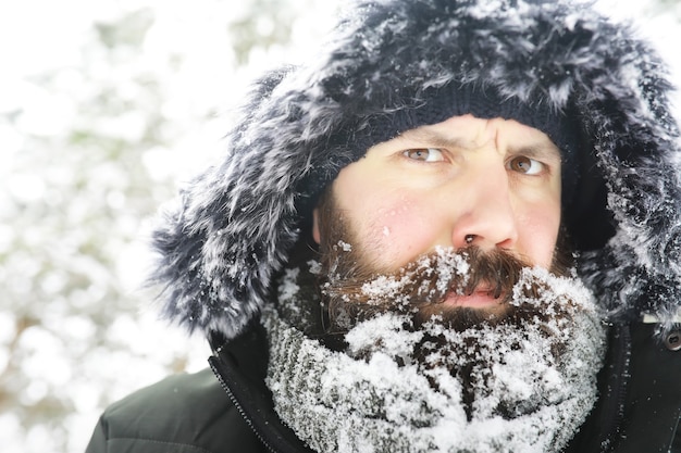 Bebaarde man in het bos van de winter. Aantrekkelijke gelukkige jonge man met baard lopen in het park.