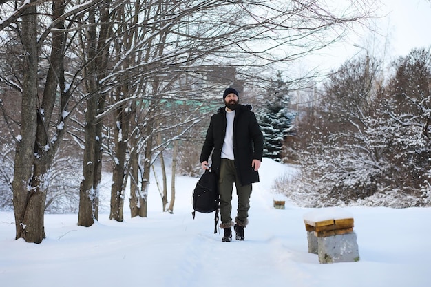 Bebaarde man in het bos van de winter. Aantrekkelijke gelukkige jonge man met baard lopen in het park.