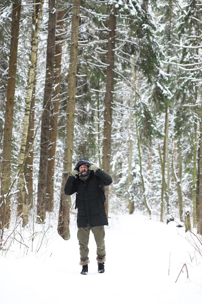 Bebaarde man in het bos van de winter. Aantrekkelijke gelukkige jonge man met baard lopen in het park.