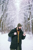 Foto bebaarde man in het bos van de winter. aantrekkelijke gelukkige jonge man met baard lopen in het park.