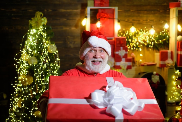 Bebaarde man in kerstkostuum met kerstcadeaubezorgservice glimlachende kerstman houdt kerst vast