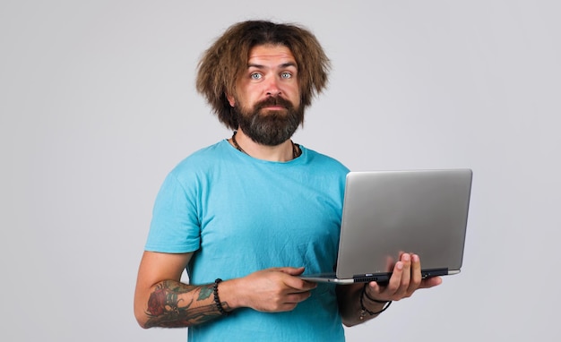 Bebaarde man in t-shirt met laptop computeronderwijs studeren en studentenleven