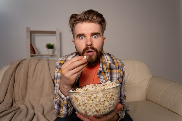 Bebaarde man kijken naar film of sport games tv popcorn eten in huis 's nachts bioscoop kampioenschap en