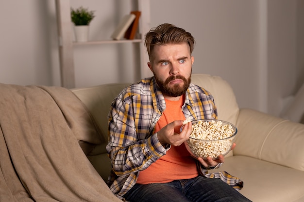 Bebaarde man kijken naar film of sport games tv popcorn eten in huis 's nachts bioscoop kampioenschap en