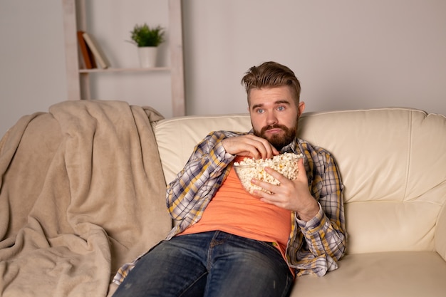 Bebaarde man kijken naar film of sport games Tv popcorn eten in huis 's nachts. Bioscoop, kampioenschap