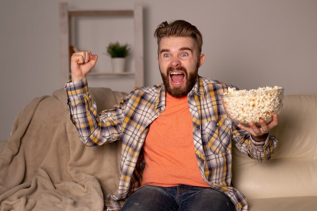 Bebaarde man kijken naar film of sport games Tv popcorn eten in huis 's nachts. Bioscoop, kampioenschap