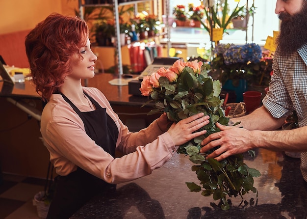 Bebaarde man koopt boeket bloemen bij een bloemenwinkel.