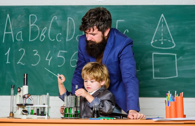 Bebaarde man leraar met kleine jongen vader en zoon op school leerling kind in de scheikunde klas vertrouwen charisma Terug naar school Science chemie concept gericht op examen