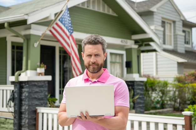 Bebaarde man makelaar koopt huis online op laptop eigendom