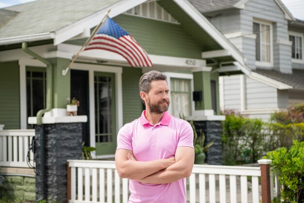 Bebaarde man makelaar verkopen of verhuren huis met Amerikaanse vlag thuis