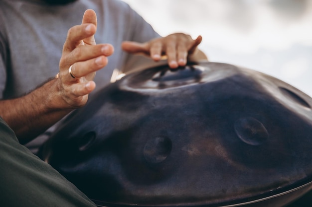 bebaarde man met een unieke handgemaakte muziekinstrument handpan spelen op de top van een berg