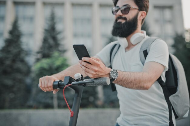 Bebaarde man met smartphone op scooter