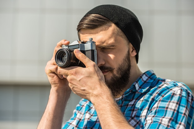 Bebaarde man met vintage camera maakt een foto.