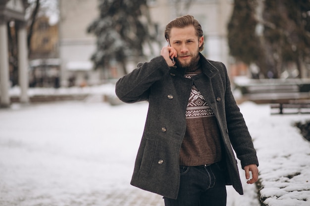 Bebaarde man praten aan de telefoon in de straat in de winter