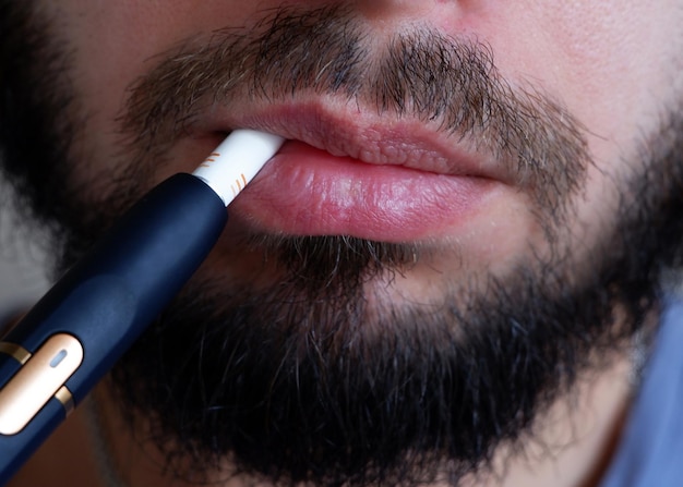 Bebaarde man rookt een elektronische sigaret close-up