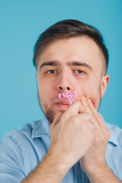 bebaarde man scheert roze scheermes op blauwe achtergrond