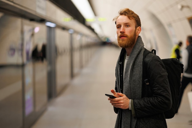 Bebaarde man staat op het perron van een metrostation