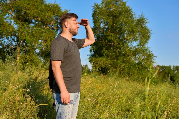 Bebaarde man van middelbare leeftijd met een rugzak op een wandeling die naar de horizon kijkt