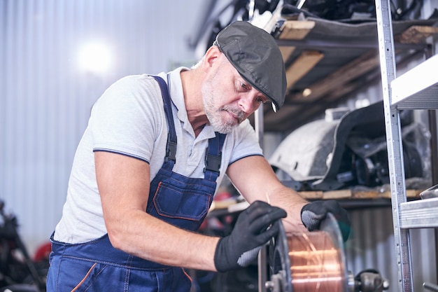 Bebaarde monteur met koperdraad bij reparatieservicestation