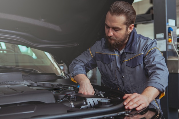 Bebaarde monteur werken bij auto tankstation