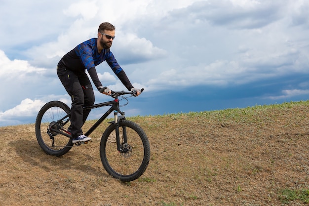 Bebaarde mountainbiker rijdt bergen tegen de prachtige lucht