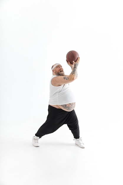 Bebaarde overgewicht getatoeëerde man met basketbal bal op witte achtergrond