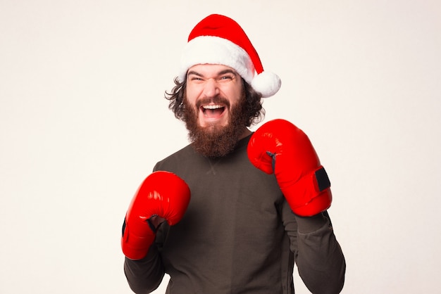 Bebaarde schreeuwende man staat klaar om aan te vallen, terwijl hij een kerstmuts en bokshandschoenen draagt.