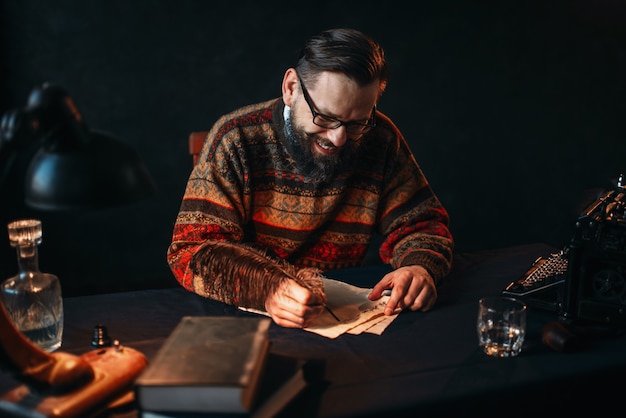 Bebaarde schrijver in glazen schrijft met een veer