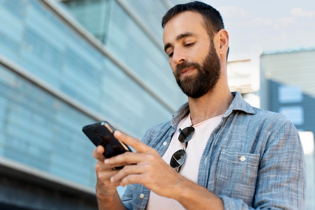 Foto bebaarde spaanse man die mobiele telefooncommunicatie online gebruikt, sms op straat leest