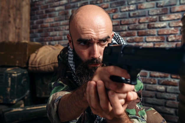 Bebaarde terrorist in uniform gericht vanuit een pistool