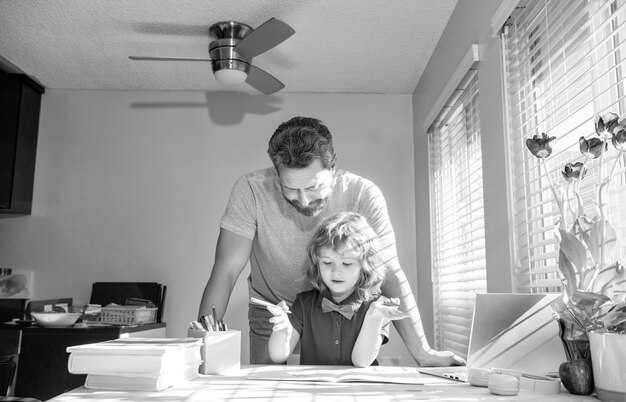 Bebaarde vader die schoolhuiswerk schrijft met zijn jongenszoon in klassikale les