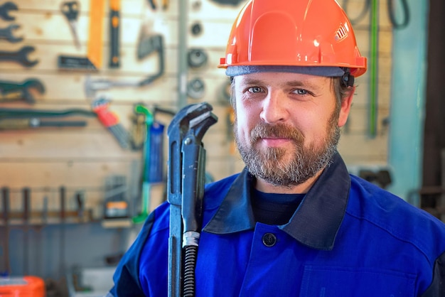 Bebaarde werkende loodgieter met grote moersleutel in de hand