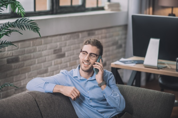 Bebaarde zakenman in blauw shirt praten aan de telefoon