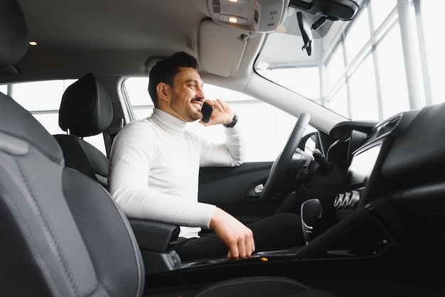 Bebaarde zakenman met behulp van mobiele telefoon, man in luxeauto