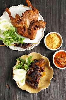 Жареная во фритюре утка bebek goreng популярное индонезийское меню, подается со свежими зелеными овощами и пастой sambal red chili
