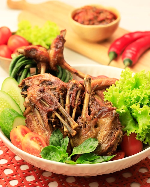 Bebek Goreng. Popular Indonesian Dish of Deep-fried Duck, Accompanied with Fresh Green Vegetables, Spicy Mango Pickles and Chili Paste.