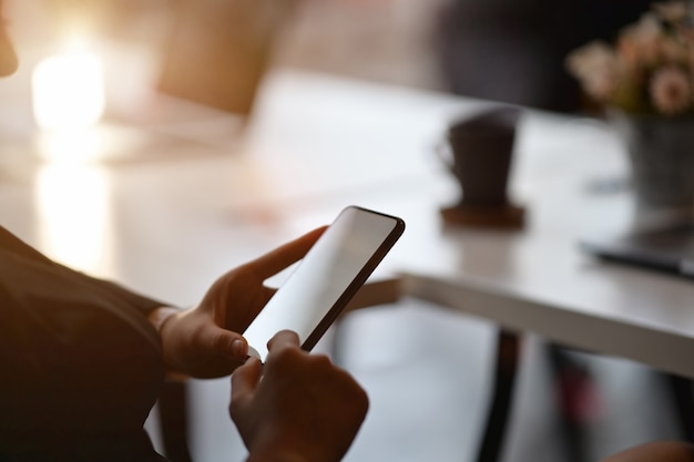 Bebouwd schot van een jonge onderneemster die op een smartphone in een modern bureau gebruiken