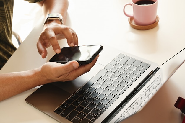 Bebouwd schot van zakenman die mobiele telefoon op werkruimte met behulp van.