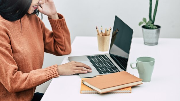 Bebouwde geschotene creatieve vrouw die met computerlaptop aan lijst werken.