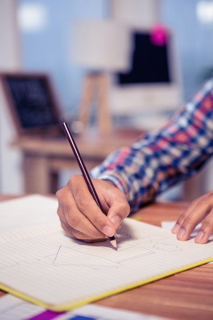 Bebouwde hand van het huis van de zakenmantekening in boek bij bureau in bureau