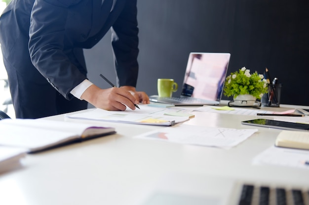 Bebouwde ontsproten foto van zakenman werkende financiën op papier met computer in bureau.