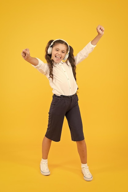 Because Im happy Happy small girl listening to music on yellow background Little child enjoying song playing in headphones with smile on happy face Happy music for kids